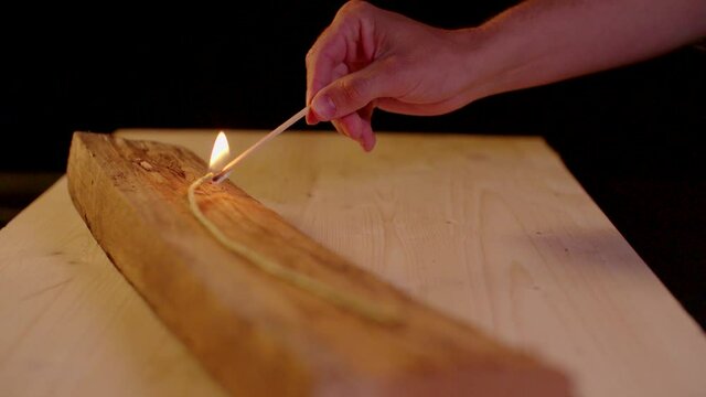 Fuse burning in slow motion on woodpiece with black background