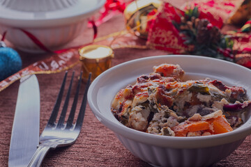 Healthy Christmas vegetarian bake in a bowl at festive table.