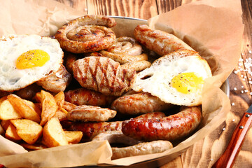 bavarian sausage plate with potatoes and fried egg. Grilled sausages closeup. Top view with copy space Appetizing beer snacks set.
