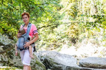 Naklejka na ściany i meble Woman Hiker trekking in mountains with child in backpack . 