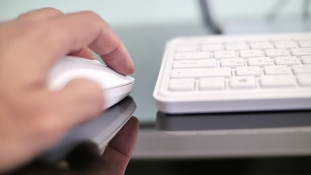 Left handed computer user, left hand holds mouse, working, typing on keyboard