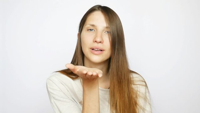 A very beautiful young lady blows a kiss against white background