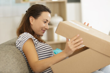 woman sitting on the sofa opening a box