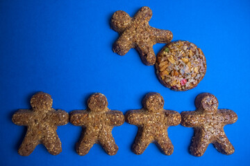 cookie figures of men on blue background. Flat lay shot of freshly bakery gingerbread cookies man. Simple idea of community and capitalism