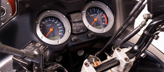 Obraz premium The arrow speedometer of a motorcycle on the steering wheel closeup. Colored dashboard with sport bike handles, top view. Horizontal image of a tachometer gauge. Banner for web site
