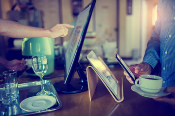 Selective focus to tablet and blurry customer using smart phone scan QR code on tablet to payment with cashier machine at counter bar in coffee shop. Accepted generate digital pay without money.