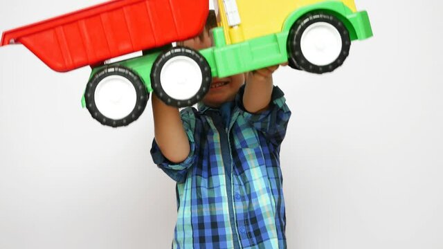 A beautiful little boy rejoices to a big toy truck in his hands