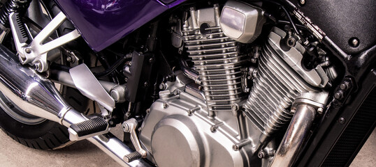 Silver v-twin shaped engine of sports motorcycle close-up. Pistons, cylinders, pedals, gearbox, back wheel motorbike. Chrome motor parts. Repair, bike maintenance in the garage. Banner for web site