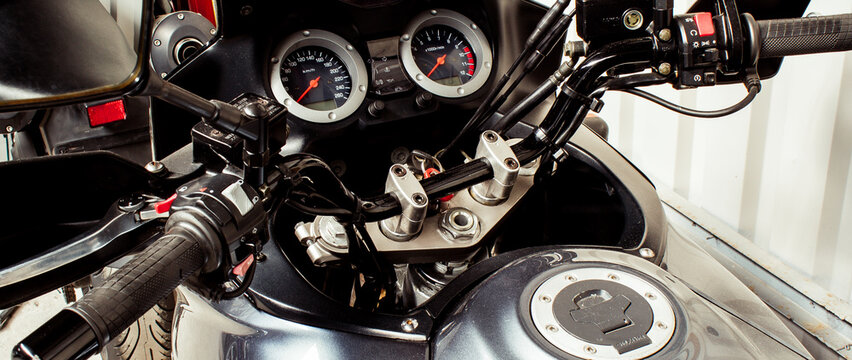 Arrow speedometer of motorcycle on steering wheel with a tank close-up. Colored dashboard with handles and glass of sport bike, top view. Horizontal image of a tachometer gauge. Banner for web site - Powered by Adobe