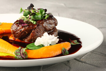filet mignon with mashed pumpkin and microgreen in white plate on concrete background