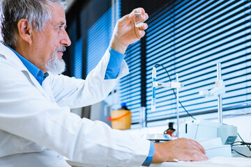 Senior male researcher carrying out scientific research in a lab (shallow DOF; color toned image)