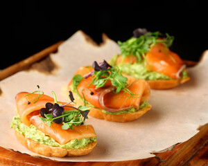 Selection of tasty bruschetta or canapes with salmon closeup. salmon tapas with guacamole and topped microgreen