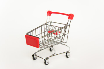 empty miniature red trolley for shopping at an angle on a white background
