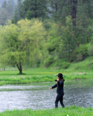 Fototapeta na wymiar Woman fly fishing in pond while raining.