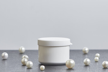 white jar of cosmetic pearls on a gray background. copyspace. mockup. side view