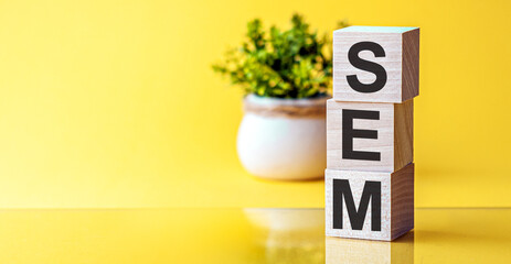 Word SEM made with wood building blocks, stock image, yellow background