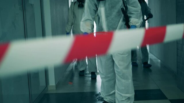 Disinfectors spray antiseptic in corridor during pandemic.