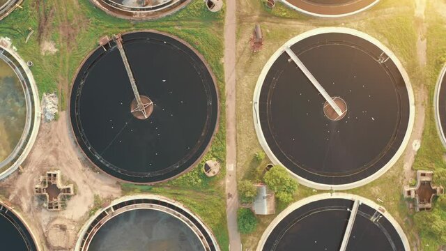 Round radial sumps or sedimentation tanks in sewage treatment plant, aerial top view in sunlight