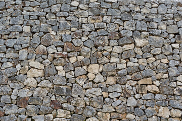 grey and reddish stone wall. antique stone wall. stone wall of different sizes in horizontal