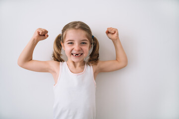 portrait of a blonde girl showing the strength of her arms on a white background