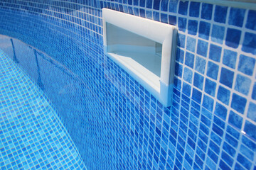 Drain hole in the pool with blue tile. Pool filtration system. Clean water.