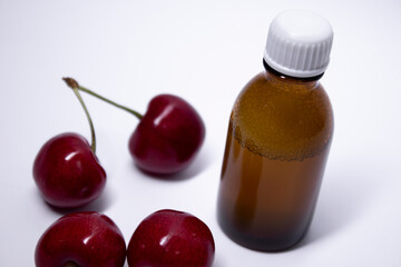 little liquid bottle with no label near cherry. body care and beauty concept. Copy space. High quality photo
