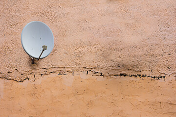 Satellite dish antenna on the old house wall or cloudy sky background