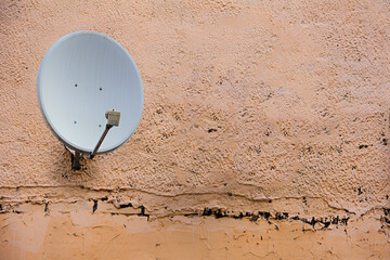 Satellite dish antenna on the old house wall or cloudy sky background