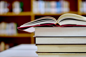 Open Book on wood table and blurred bookshelf in the library, education background, back to school concept.