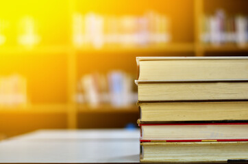 Stack of books and blurred bookshelf in the library, education background, back to school concept.