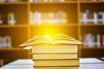 Open Book on wood table and blurred bookshelf in the library, education background, back to school concept.
