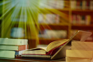 Stack of books with laptop on table in library, image selective focus and blurred bookshelf in the library, education background, back to school concept.
