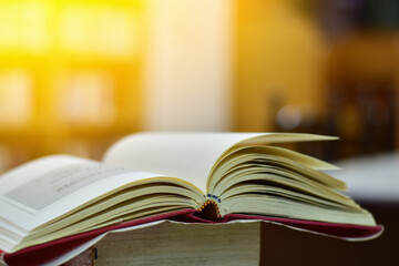Open Book on wood table and blurred bookshelf in the library, education background, back to school concept.