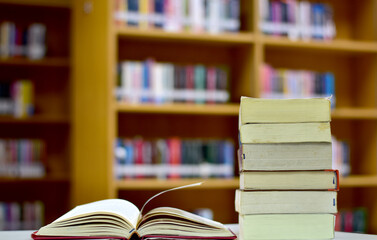 Open Book on wood table and blurred bookshelf in the library, education background, back to school concept.