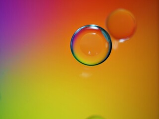 Closeup yellow orange oil bubbles with colorful background and blurred droplets ,macro image ,sweet pastel color ,rainbow and colorful balloons background, abstract background