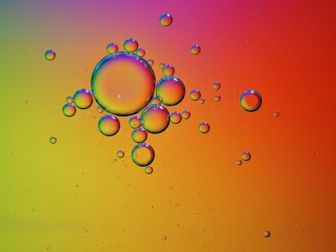 Closeup red yellow oil bubbles with colorful background and blurred droplets ,macro image ,sweet pastel color ,rainbow and colorful balloons background, abstract background