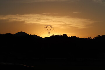 Sunset in the mountains. Transmission line tower.