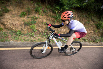 Obraz premium Kobieta na rowerze w dół stoku z dużą prędkością na górskim szlaku