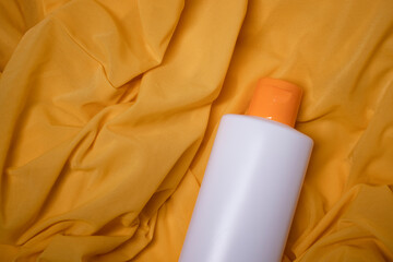 a yellow shampoo bottle with yellow neck and no label in a silk yellow fabric. body care and beauty...