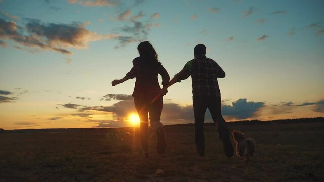 happy family couple and dog runs hands at sunset on a hilltop. concept of team business concept travel freedom victory happiness teamwork. happy family parents hold hands run in the rays lifestyle of