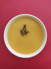 bowl of yellow vegetable soup on red background 
