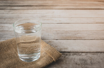 glass of water on wooden table bokeh background - vintage style picture.