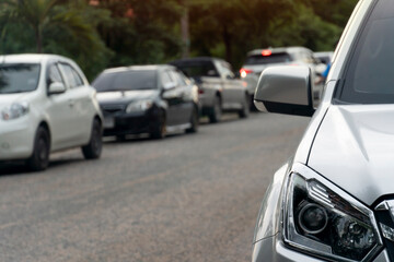 Luxury front corner of bronze car on the road. Traffic is parked in the queue of several cars across the asphalt road.