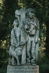 Fototapeta na wymiar Statue in the middle of a park in the English countryside, two men and a dog