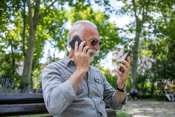 Old man compare two smartphones