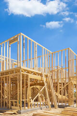 New residential construction home framing. Blue sky and white clouds background.