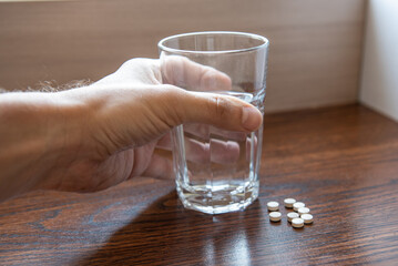healthy lifestyle, medicine, nutritional supplements and people concept - close up of male hands holding pills and water glass