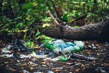 Garbage pile in forest among plants. Toxic plastic into nature everywhere. Rubbish heap in park...