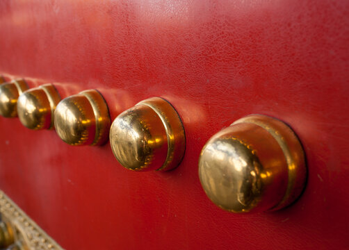 Row of giant golden knobs on bright red door in Forbidden City. 