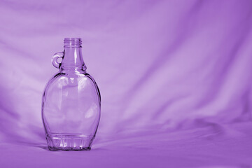 Isolate of glass maple syrup bottle in purple. Concept for zero waste lifestyle, reduction of single use plastics, and environmental protection.